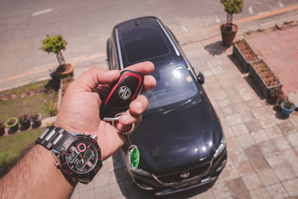 Hands exchanging car keys beside a vehicle, illustrating a vehicle donation